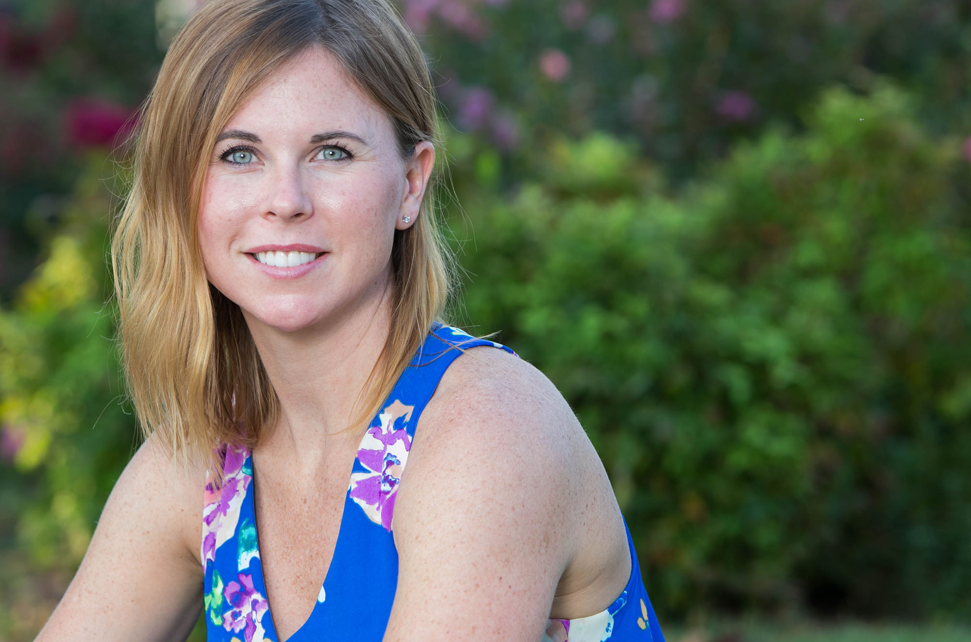 smiling woman sitting outside wearing blue floral tank top